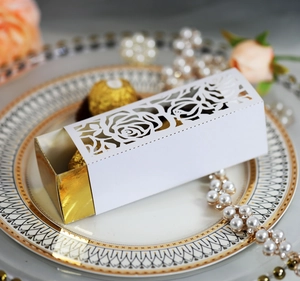 Close-up of white laser-cut rose gift box with golden inner tray on a porcelain plate