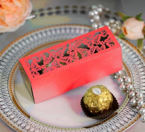 Detail showing red laser-cut candy box with hollow butterfly patterns for weddings
