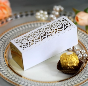 Detail of laser-cut white favor box with golden interior and intricate vine patterns
