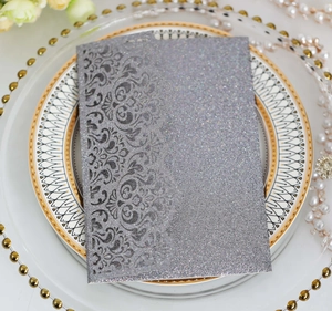 Macro shot of silver glitter laser-cut invitation sleeve with intricate scrollwork
