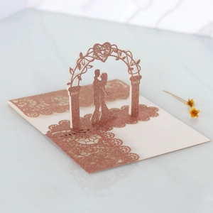 Macro view of rose gold glitter laser-cut 3D wedding invitation with kissing couple