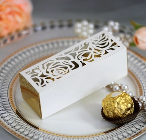 Laser-cut white wedding favor box with hollow rose patterns and golden mirror edges