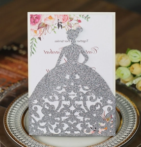 Macro detail of silver glitter laser-cut invitation featuring an elegant dress silhouette