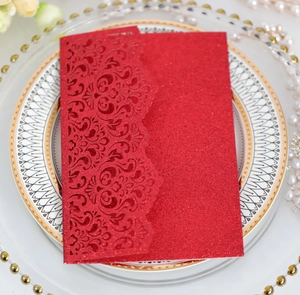 Macro shot of laser-cut red glitter invitation card with floral patterns on a ceramic plate