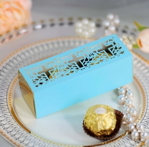 Detail of laser-cut cross patterns on light blue wedding candy gift box with gold interior