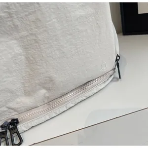 Detail of light grey nylon fabric with embossed logo and black heavy-duty zipper