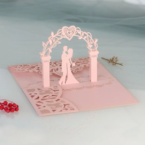 Detail of pink 3D laser-cut wedding invitation featuring a romantic couple under floral arch