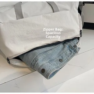 Detail view of white travel bag showing a large zipper side pocket with high capacity