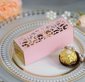 Macro shot of laser-cut pink and gold hollow wedding favor box with floral patterns