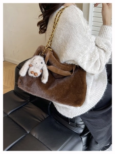 Dettaglio borsa tote in peluche marrone con catena dorata e ciondolo a coniglio
