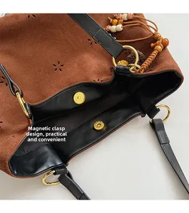 Detail of the brown suede tote bag showing the gold magnetic closure and interior lining