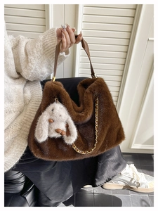 Dettaglio della borsa tote in peluche marrone con catena dorata e ciondolo a coniglietto