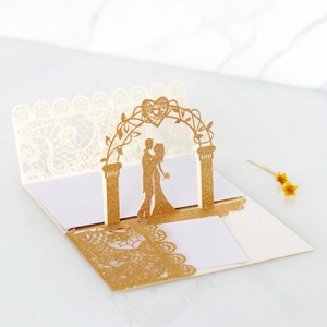 Macro detail of 3D laser cut wedding invitation featuring golden glitter heart arch