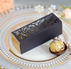 Macro view of laser-cut rose patterns on elegant black and gold gift packaging boxes
