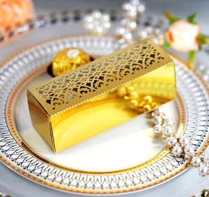 Detailed laser-cut gold candy box with intricate patterns and chocolate inside for weddings