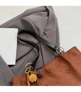 Detail of laser-cut flower patterns on dark brown suede tote with gold ring connector
