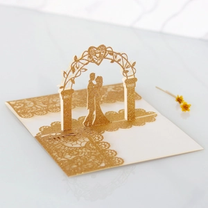 Macro view of 3D laser-cut wedding card with golden glitter finish and couple silhouette