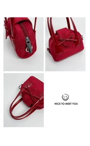 Detalle de mini bolso de terciopelo rojo con lazo y cierre de cremallera metálica