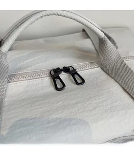 Detail of smooth black dual metal zippers on a gray large capacity travel bag
