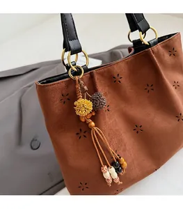 Close-up of brown suede tote bag featuring star cutouts and colorful tassel detail