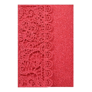 Detail of red glitter wedding invitation with laser-cut floral lace and sparkling texture