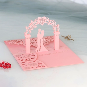 Macro detail of laser-cut pink 3D pop-up wedding card with kissing couple inside