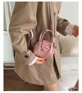 Detalle del mini bolso rosa de ante con lazo decorativo y asa de anillo metálico