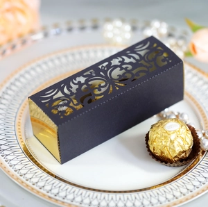 Macro detail of laser-cut black and gold wedding favor box with ornate scroll patterns