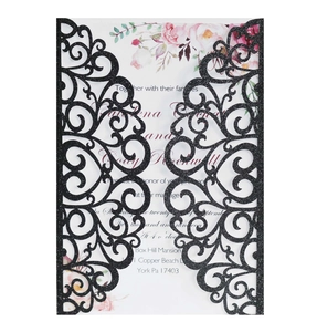 Detail of laser-cut black glitter wedding invitation with heart vines and floral insert
