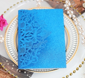 Détail d'invitation de mariage pailletée bleue avec motif floral en dentelle découpé