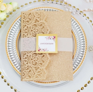 Detailed laser-cut gold glitter wedding invitation with floral tag and cream rose decor