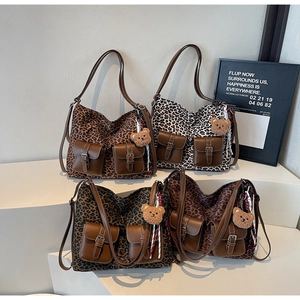 Detail of leopard print tote bags with brown leather pockets and plush bear charms