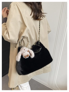 Dettaglio borsa shopper in peluche nera con catena dorata e ciondolo a forma di coniglio