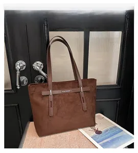 Dettaglio della borsa tote in pelle scamosciata marrone con cinturino a fibbia decorativo