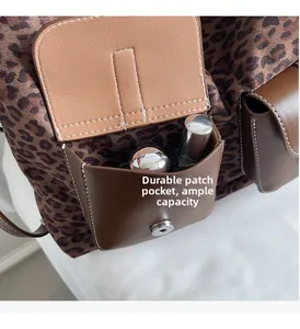 Detail of leopard print tote featuring a brown leather pocket with magnetic closure and lipstick