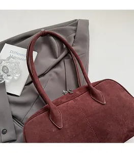 Nahaufnahme der burgunderroten Wildledertasche mit schmalen Riemen auf grauem Sakko