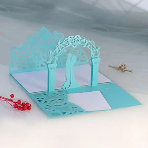 Detail of laser-cut 3D wedding invitation with romantic couple and floral heart arch