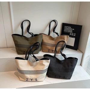 Detailed display of four large canvas tote bags in olive, mustard, cream, and black colors