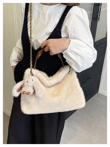 Dettaglio borsa tote in peluche bianco sporco con manico in pelle e ciondolo a coniglio