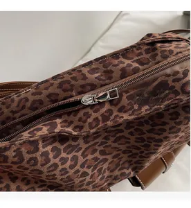Close-up of smooth silver metal zipper and brown leather trim on leopard print bag
