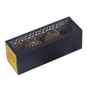 Macro view of black cardboard gift box with laser-cut gold floral patterns and vine details
