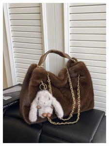 Dettaglio ravvicinato della borsa tote in peluche marrone con catena d'oro e coniglietto