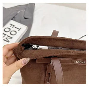 Dettaglio macro della chiusura lampo argentata sulla borsa tote in pelle scamosciata