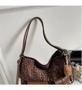 Detailed view of leopard print tote bag with brown leather handles and plush bear charm