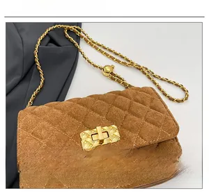 Detail of brown suede quilted crossbody bag featuring golden chain and sphere adjustment
