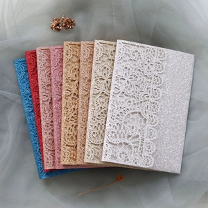 Macro detail of laser-cut lace wedding invitations in various glitter color finishes
