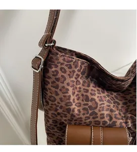 Detail of leopard print tote bag featuring brown leather strap and contrast stitching