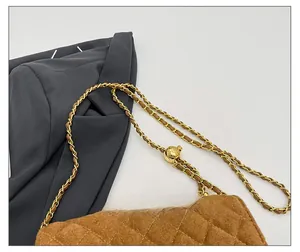 Detail of quilted brown suede crossbody bag with gold adjustable chain strap buckle