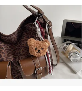Detail of plush bear charm with leopard print tote bag and woven strap accents