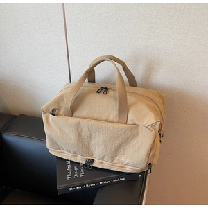 Close-up of khaki travel bag with zipper pockets and handle on a leather sofa